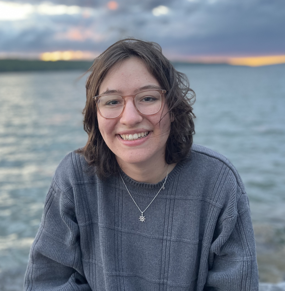 a portrait of a women sitting in front of a lake
