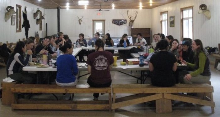 people sit around a table in a dining hall.